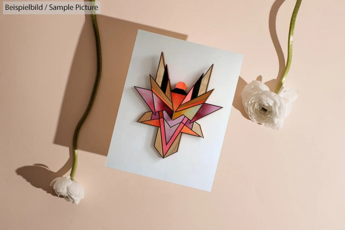 Geometric wooden art on paper with two white flowers on a beige background.