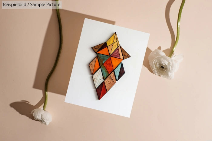 Geometric wooden artwork on paper with two white flowers on a beige background.