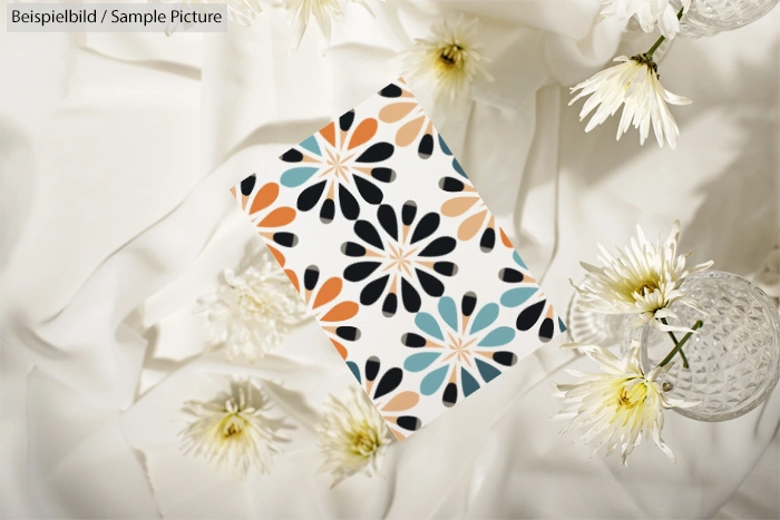 Colorful floral-patterned card on white satin with white flowers around.