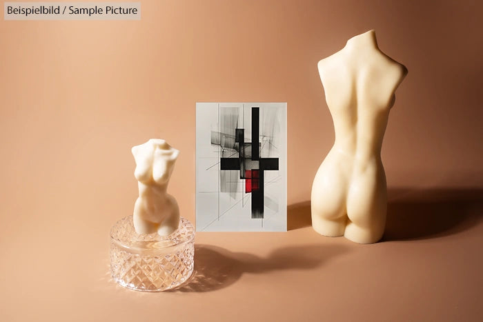 Decorative art pieces with abstract painting and sculpted torsos on a beige surface.