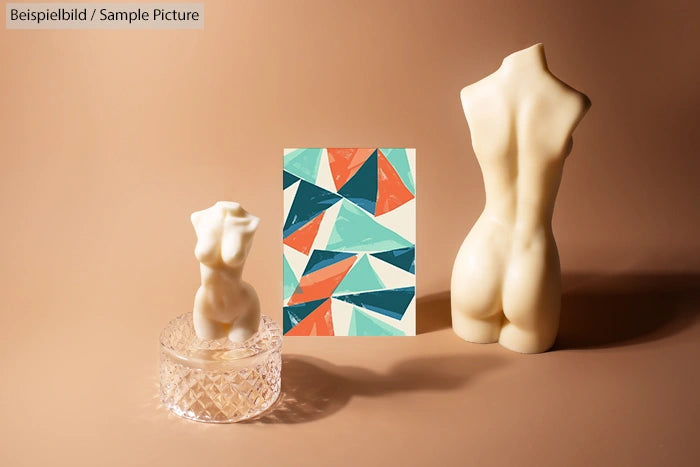 Two sculptured busts and a geometric abstract painting on a brown surface.