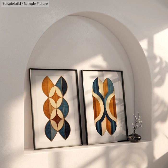 Two framed abstract geometric artworks on a shelf with a small vase under arched niche and soft light.