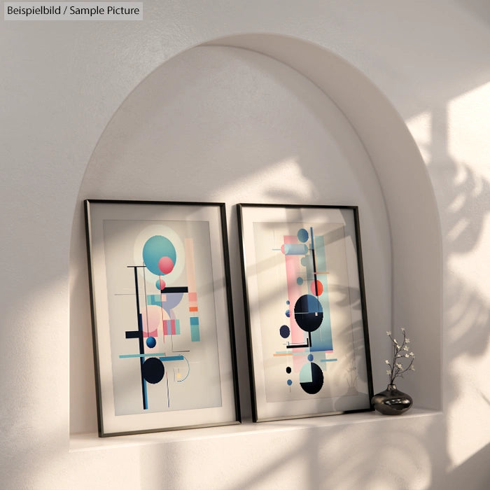 Two abstract geometric framed artworks in an arched alcove with soft light and shadows on a white wall.