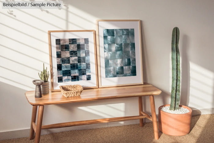 Minimal room with wooden bench, two abstract paintings, a tall cactus in pot, and a woven basket under soft natural light.