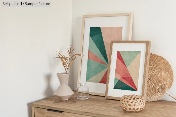 Framed geometric art prints and decorative items on a wooden table in a modern, minimalist room.