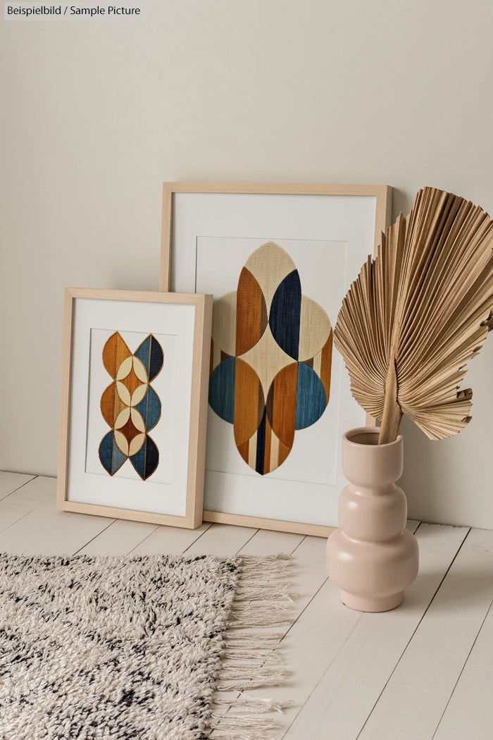 Bohemian-style room decor with geometric framed art, dried palm leaf in vase, and textured rug on wooden floor.