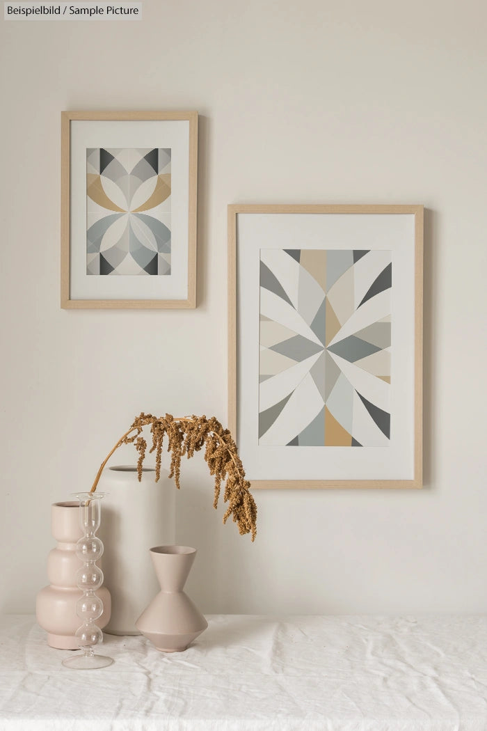 Minimalist home decor with geometric framed art and vases on a table.