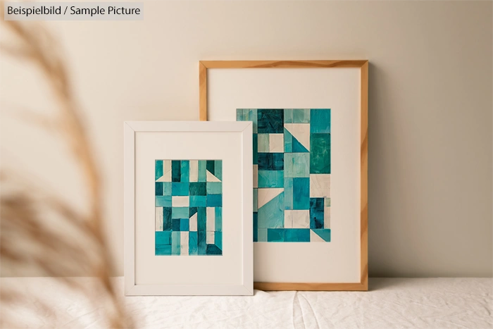 Two framed abstract paintings with blue and teal geometric shapes, leaning against a neutral wall.