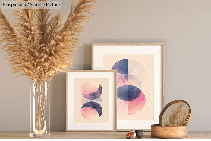 Framed abstract art with geometric shapes; vase with dried grass and a round mirror on a wooden shelf.