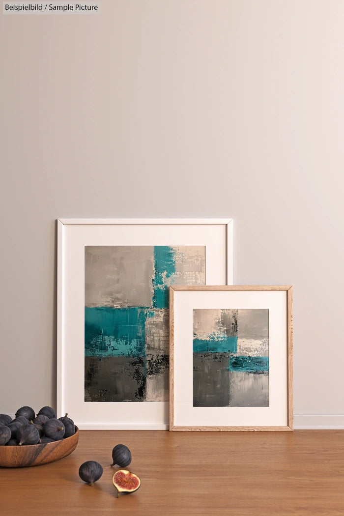 Modern abstract art in frames with teal and beige squares, displayed on a minimalist shelf beside a bowl of figs.