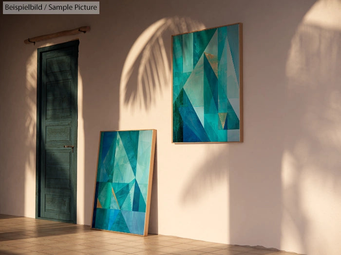 Abstract geometric art pieces in green and teal hues on a sunlit wall with a wooden door.