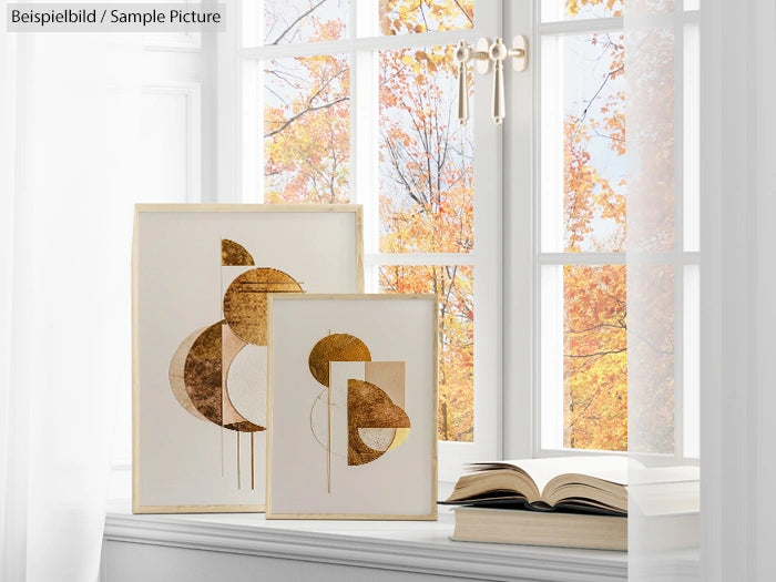 Abstract gold geometric artwork near window with open book and autumn trees outside.