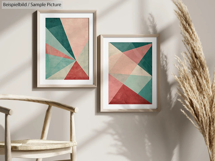 Two framed geometric abstract art prints on a beige wall, with a wooden chair and pampas grass nearby.