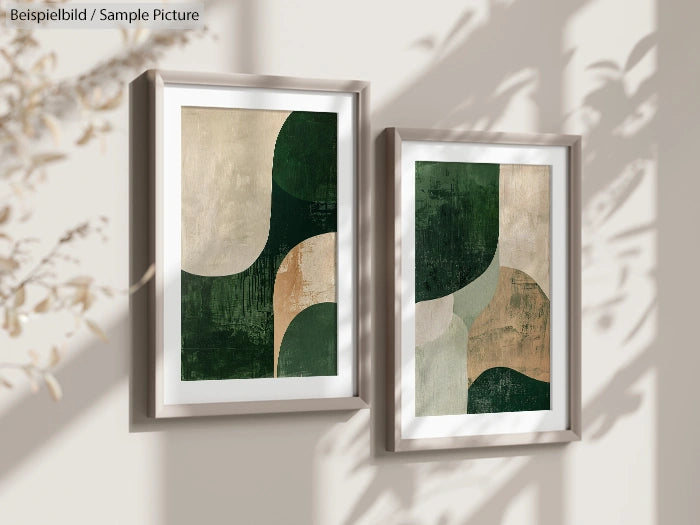 Two abstract artworks with green and beige shapes in frames on a sunlit wall with shadows of leaves.