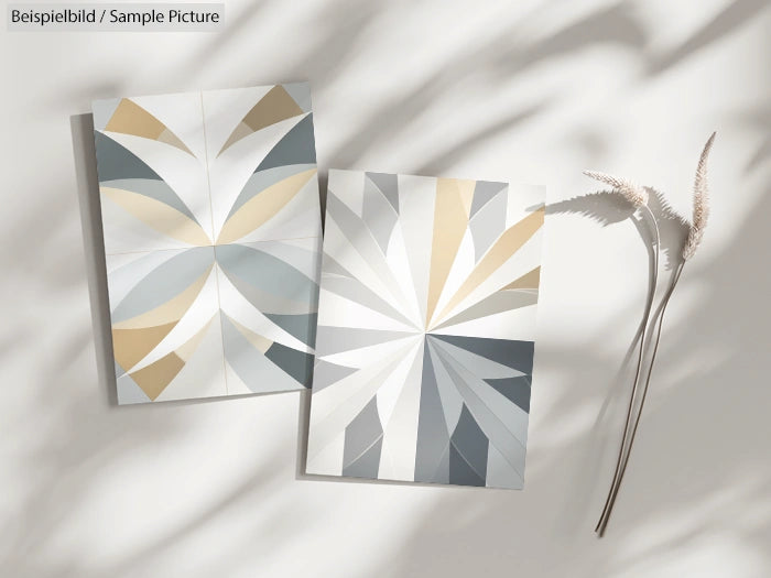 Two elegant panels with geometric patterns in beige, gray, and white; displayed on a sunlit surface with cast shadows.