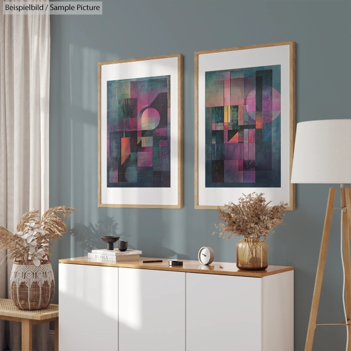 Modern living room with abstract geometric art on wall, framed prints above a white cabinet, beige lamp and decor.