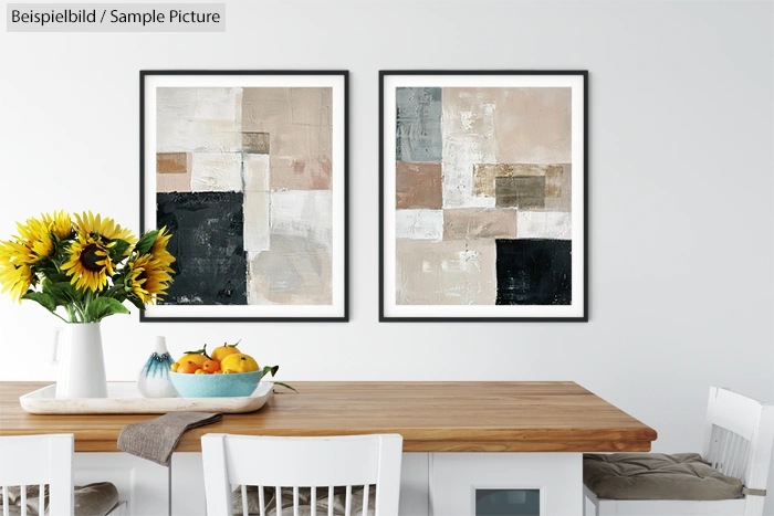 Modern kitchen with wooden table, white chairs, abstract paintings, vase of sunflowers, and fruit bowl.