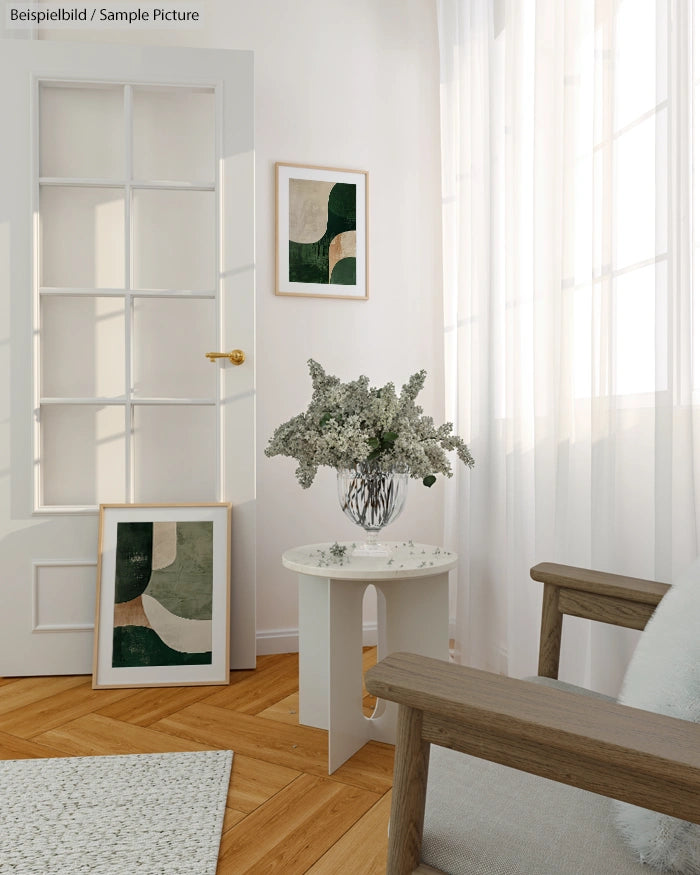 Minimalist living room with abstract paintings, a vase of flowers on a side table, and wooden furniture.