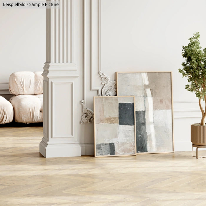 Minimalist room with abstract paintings, wooden floor, white walls, and green potted plant beside a pillar.