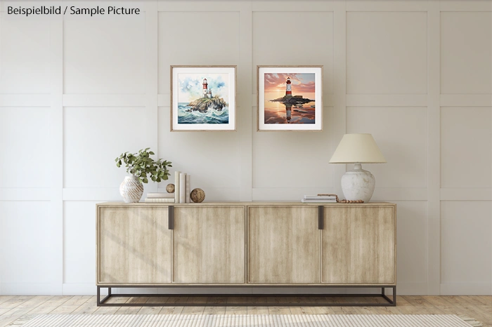 Minimalist living room with a wooden sideboard, two framed seascape paintings, a lamp, and decorative objects.