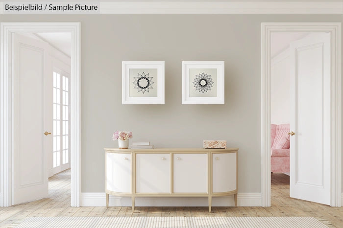 Minimalist living room with two framed mandala artworks and a white console table against a light gray wall.