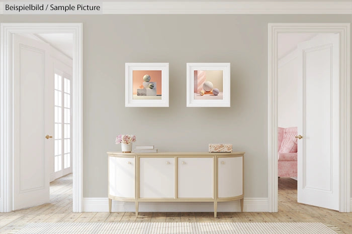 Elegant hallway with a beige console table, two modern art pieces on the wall, and a glimpse of a pink furnished room.