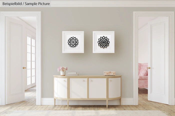 Modern living room with white console table, two framed black and white artworks, light gray walls, and wood flooring.