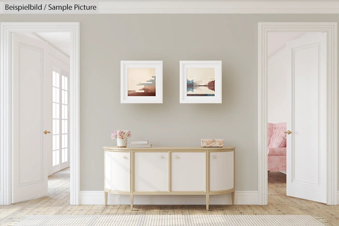 Elegant living room with grey walls, two framed artworks, and a white sideboard. Bright natural light from glass doors.