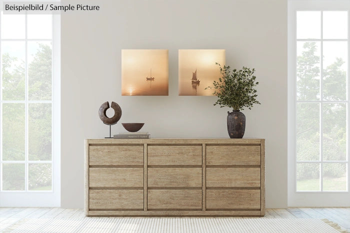 Minimalist living room with wooden dresser, artworks, ceramic vase with plant, and sculptures against large windows.