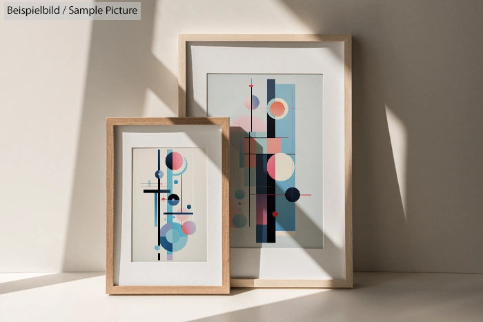 Geometric abstract art prints in wooden frames with circles and lines, against a shadowed wall.