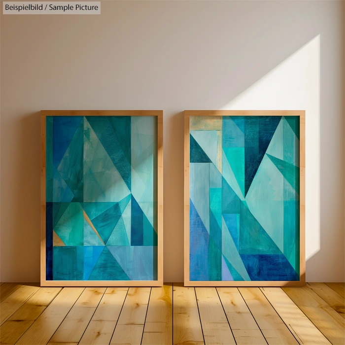 Two framed abstract paintings with geometric shapes in blue and teal tones on a wooden floor against a white wall.