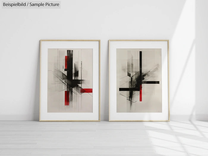 Two framed abstract artworks with black and red geometric designs on a minimalist white wall.