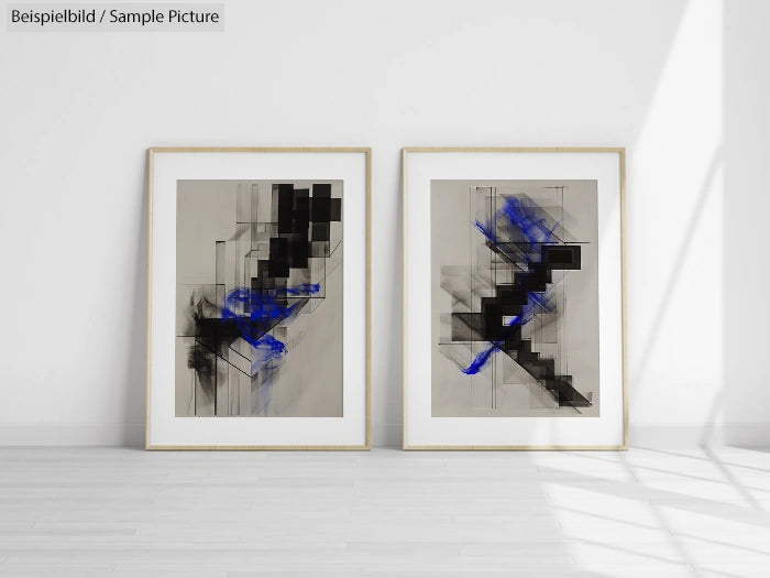 Two abstract paintings with black and blue geometric shapes in light wooden frames, displayed on a white wall.