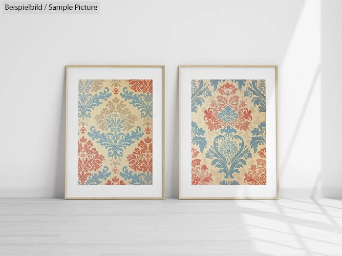 Two framed artworks with ornate floral patterns in red, blue, and beige displayed on a white wall.