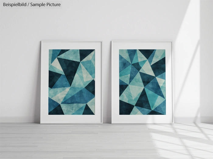 Two framed abstract geometric paintings with blue and teal triangles on a white wall, shadowed hardwood floor.