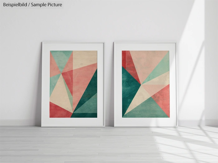 Two framed geometric art prints with pastel triangles stand side by side against a white wall in a bright room.