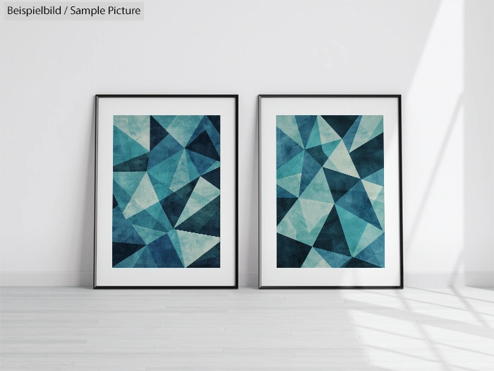 Two framed abstract art prints with blue geometric patterns, leaning against a white wall on a light wood floor.