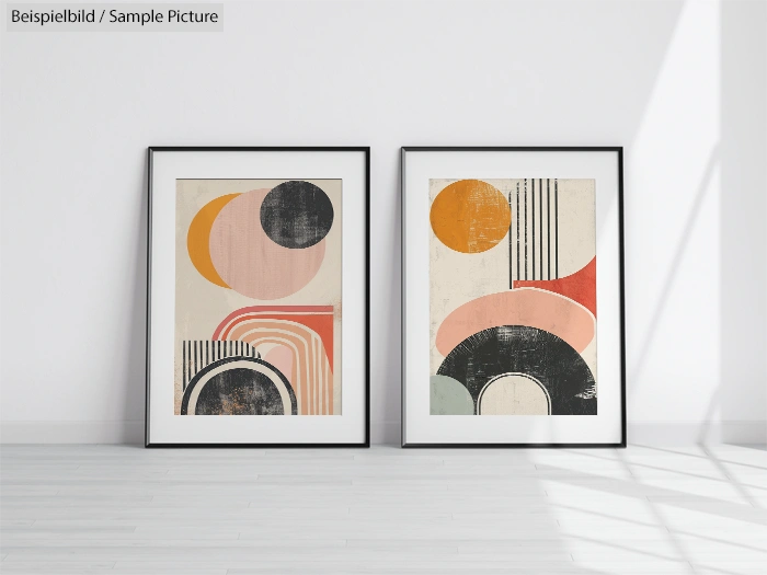 Two framed abstract geometric artworks with colorful shapes on a white wall in a bright room with wooden floor.