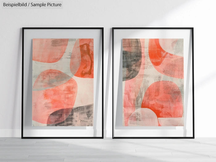 Two abstract art pieces with overlapping red, pink, and gray shapes in black frames on a white wall.