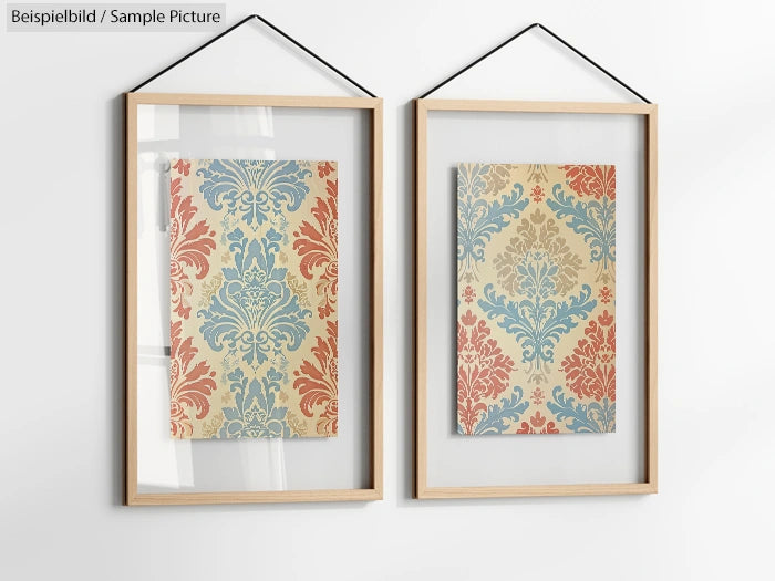 Two framed floral motif pictures with blue and red designs, hanging on a white wall.