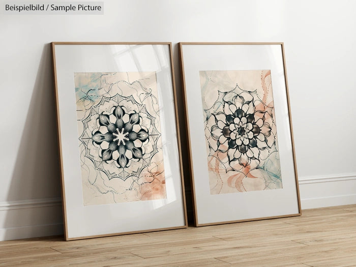 Two framed mandala artworks with floral patterns on a wooden floor against a white wall.