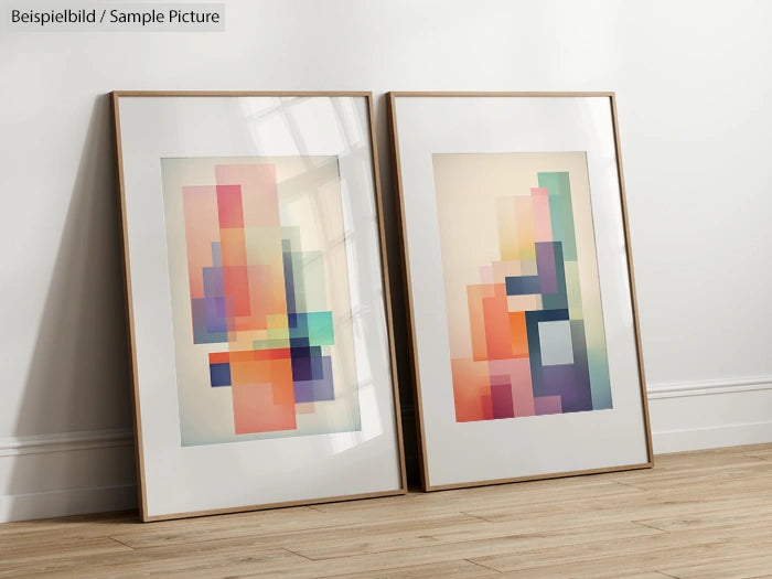 Two framed abstract paintings with pastel geometric shapes, leaning against a white wall on hardwood floor.