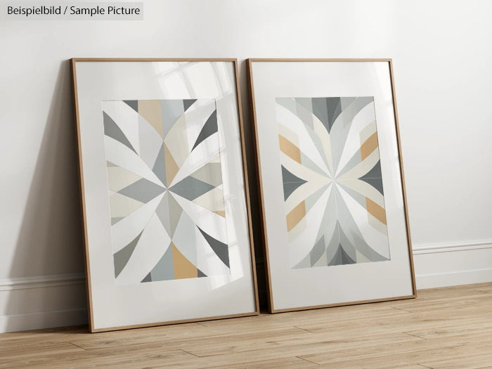 Two framed abstract geometric artworks with gray, beige, and cream tones, leaning against a white wall on a wood floor.