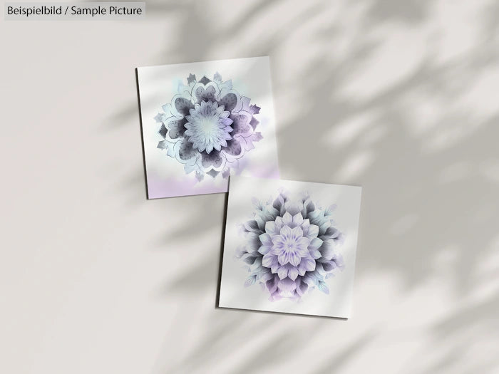 Two square floral tile designs with pastel purple and blue hues, casting shadows on a light surface.