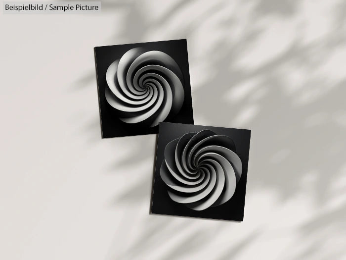 Two black square tiles with spiral designs, casting artistic shadows on a neutral background.