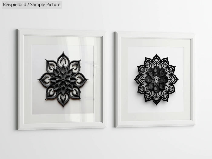 Two framed black geometric paper cut designs on a white wall.