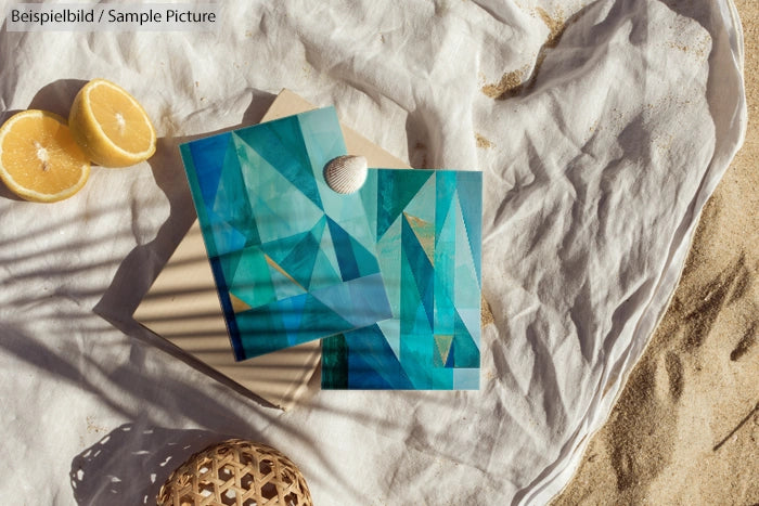 Beach scene with geometric blue artwork, sliced lemon, and sand. Shadows cast over objects creating a serene atmosphere.