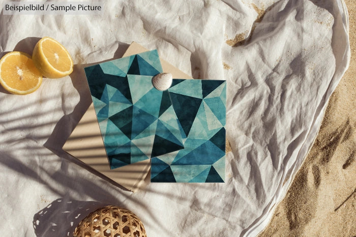 Geometric blue artwork on sandy background with cut lemons and seashell.