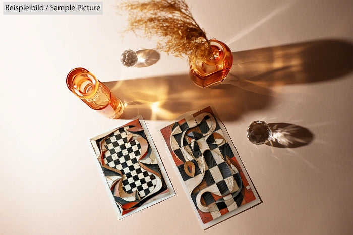 Geometric abstract art cards with checkered patterns and shadows, next to amber glass and dried plant shadow.