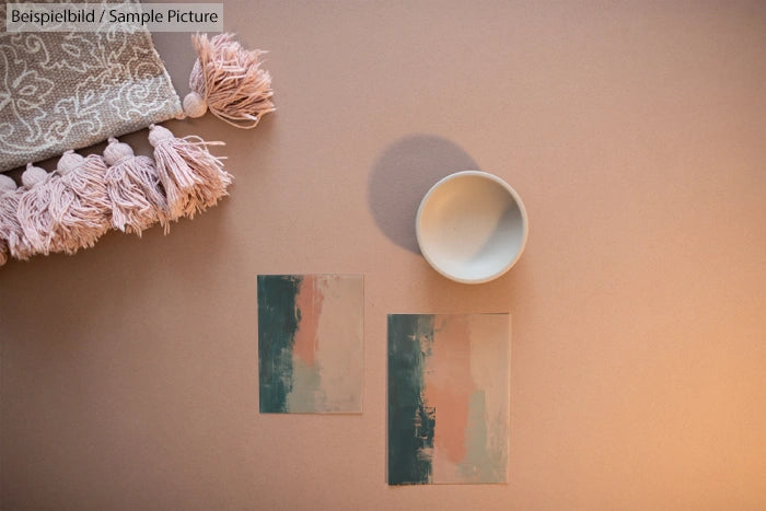 Soft pink and taupe items arranged with abstract art prints and a small bowl on a neutral background.